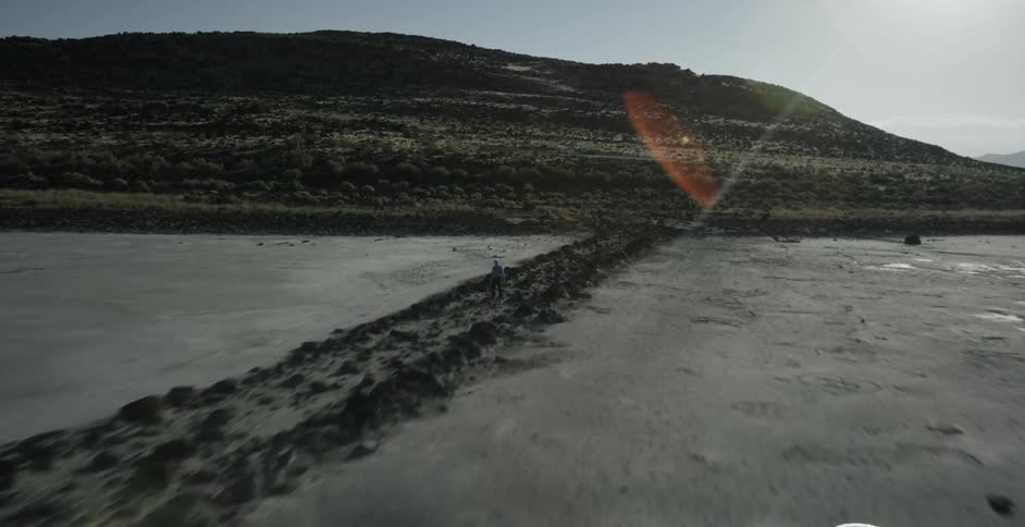 Sun shining on muddy plains and small hill