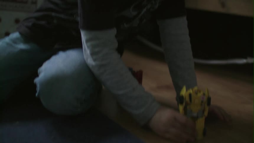 A child is playing with a yellow car