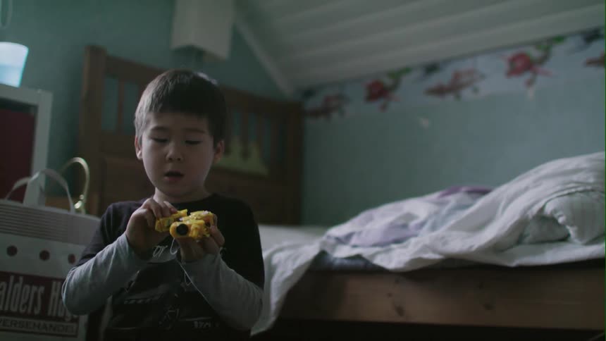 A little boy is playing in his room with a toy car