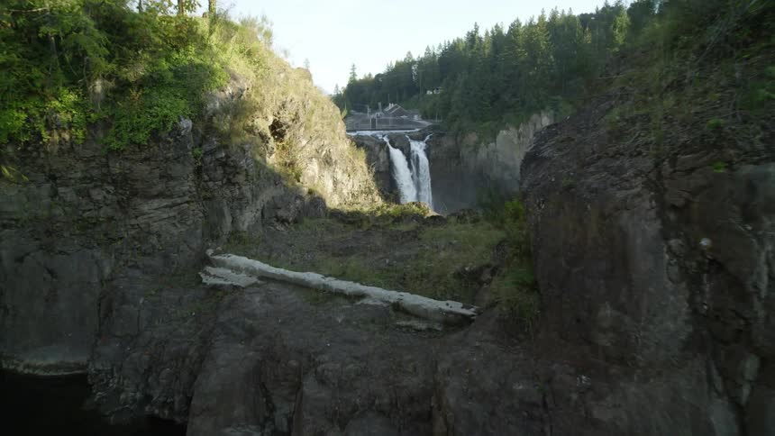A waterfall flows near a hydro power station carved into mountain cliffs