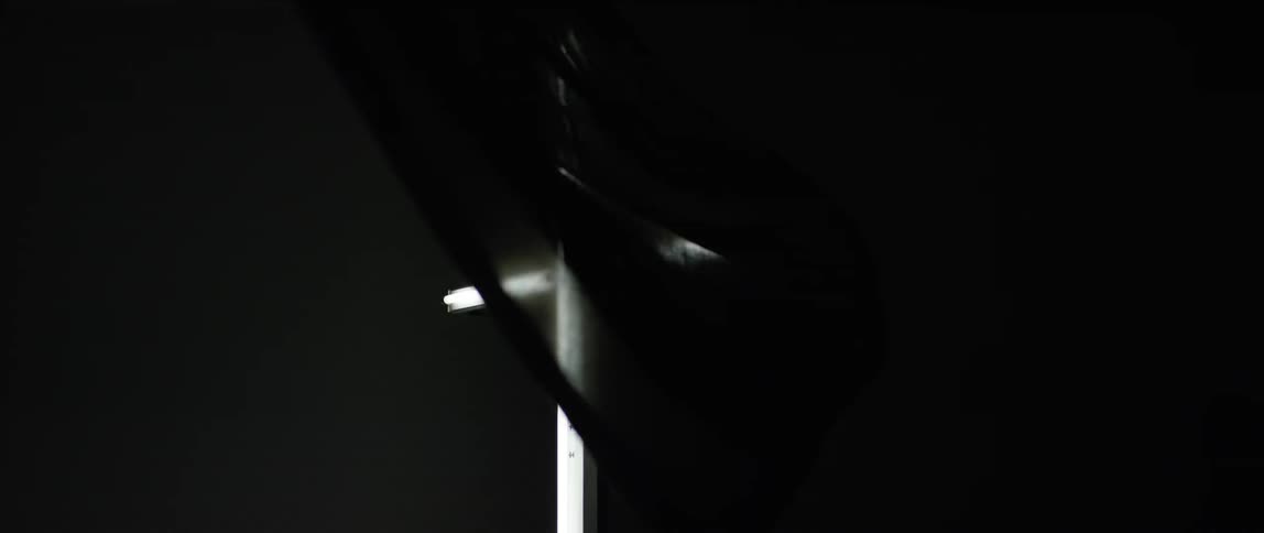 Black fabric blows around a white cross