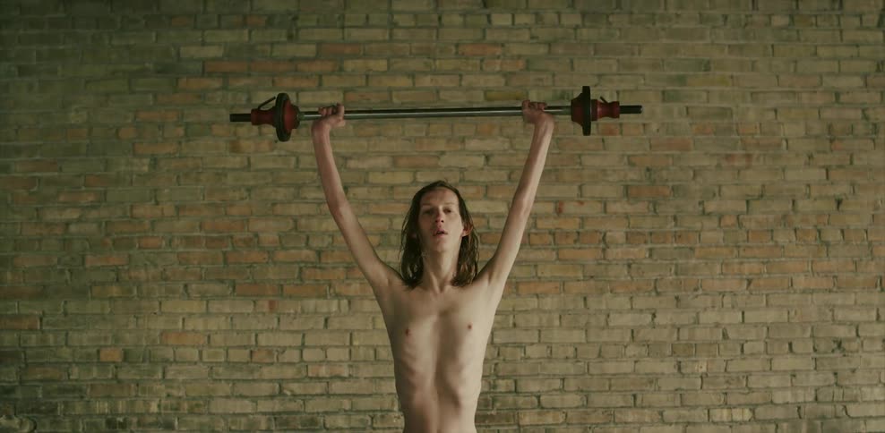 A man lifting weights in front of a brick wall