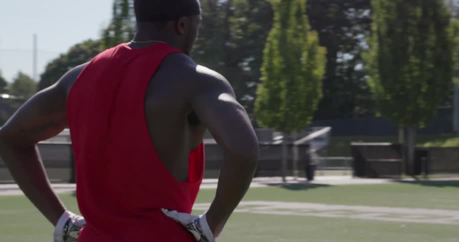 A male athlete walks with his hands on his hips