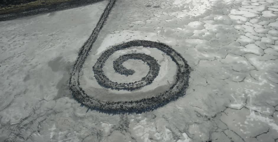 A stone spiral stretches out from a hill onto a salt flat