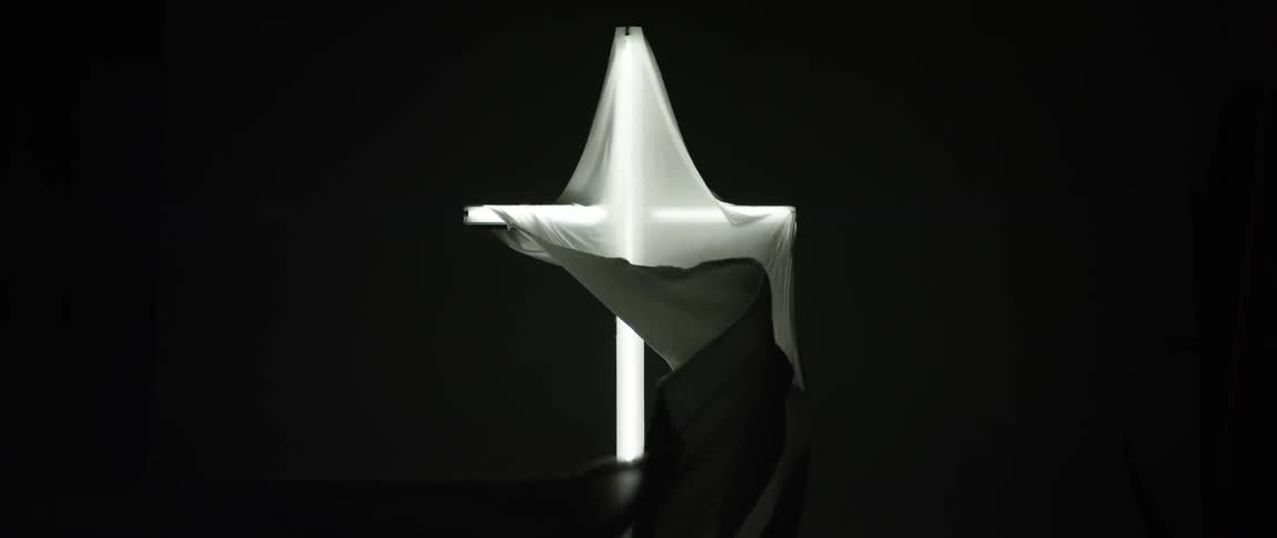 Long, gauzy material wrapped around a cross and billowing in a breeze