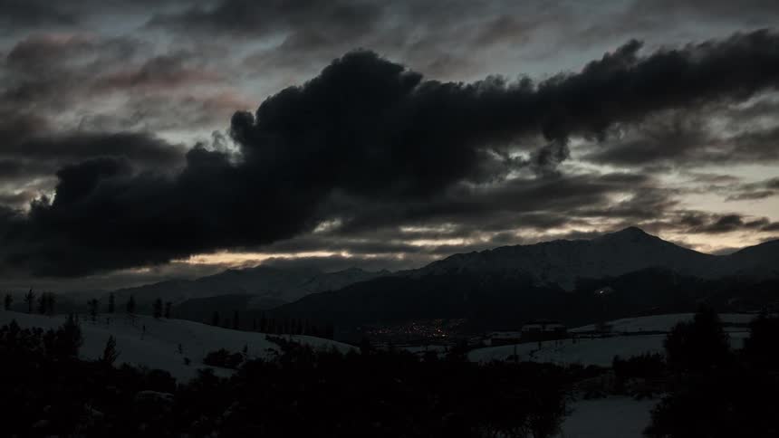 Clouds floating over snowy mountains at dusk
