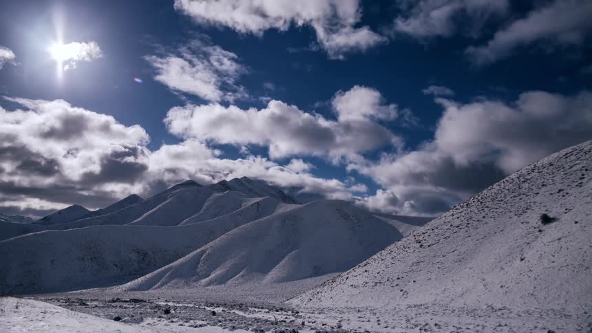 Time lapse of clouds blowing over snow-capped mountains