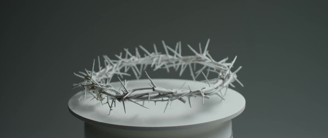 A white crown of thorns turns on a pedestal