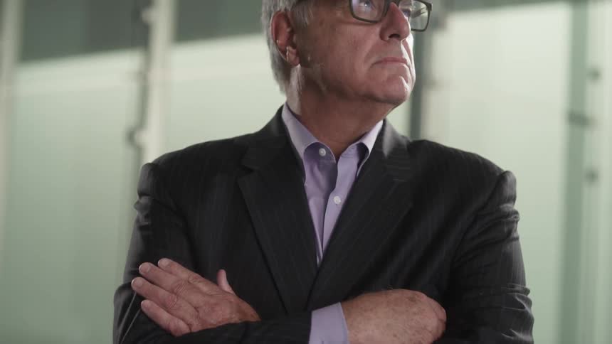 Man in a suit folding his arms and staring into the distance