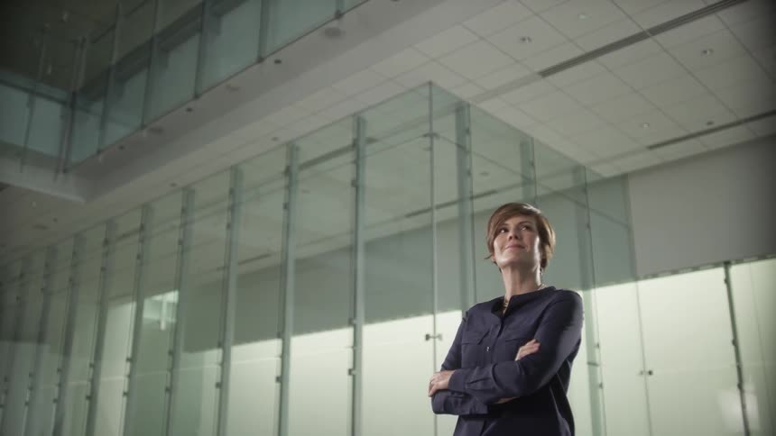 A woman stands in an empty room with her arms crossed