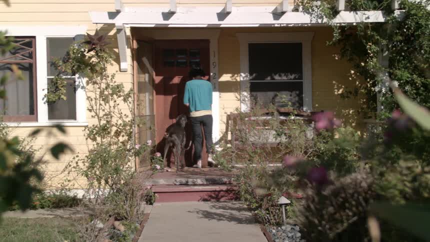 Woman with leashed dog entering a house