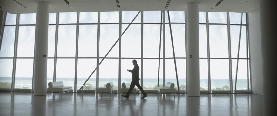 Man walking in front of floor to ceiling windows
