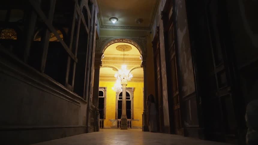 Ornate light fixtures hang above a dimly lit hallway