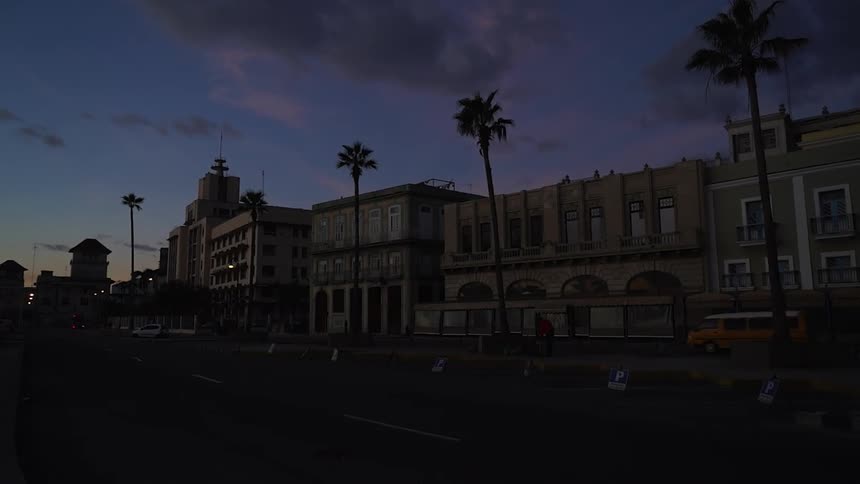 A van drives past buildings at dawn