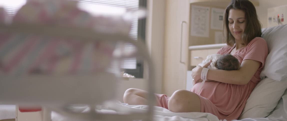 Woman sitting in a hospital bed holds an infant