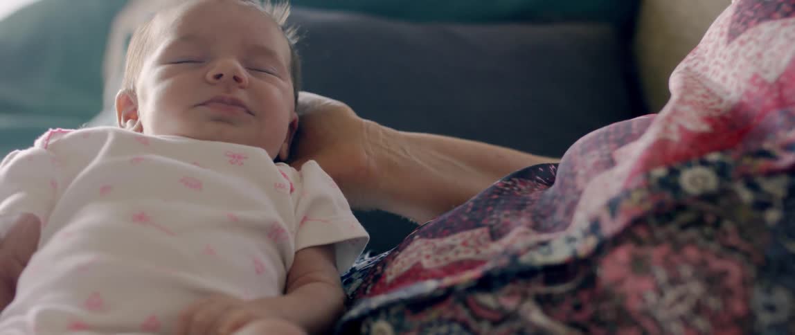 A newborn baby sleeps while a woman holds it