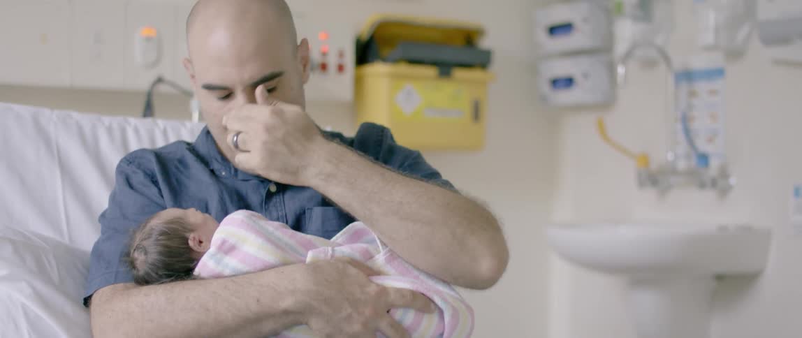 A man holds a newborn baby in his arms