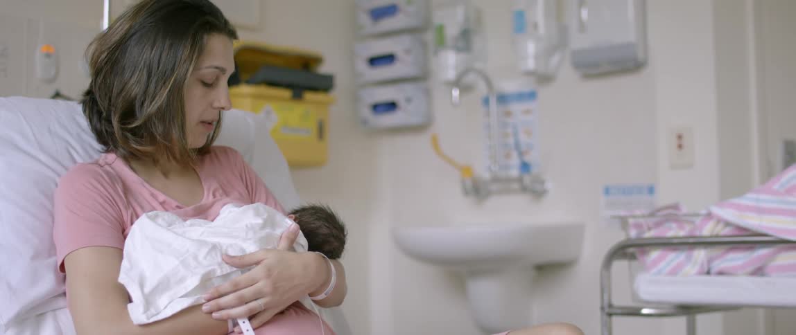A mother breastfeeds a newborn in a hospital