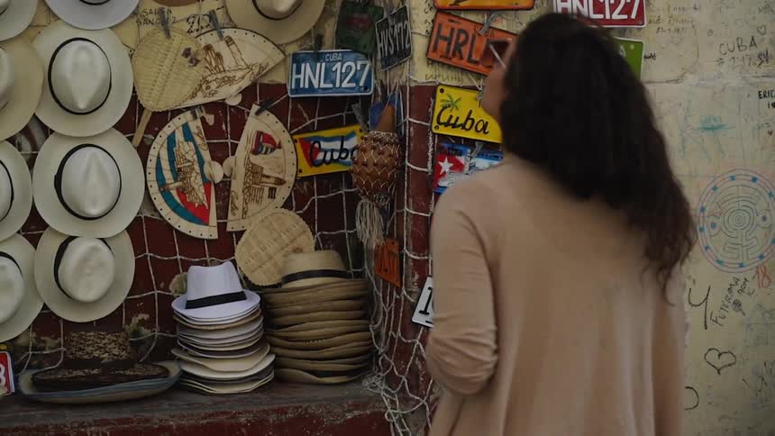 A woman is looking at a wall of hats in an outdoor stall