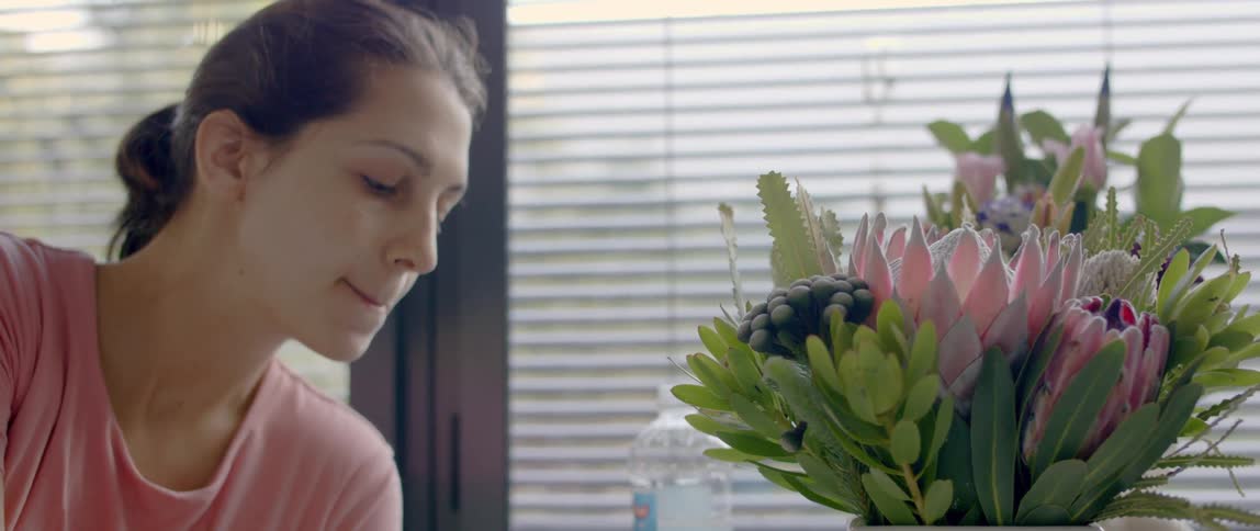 A woman sits beside a vase full of flowers