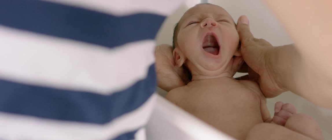 Infant being washed in a small tub by an adult