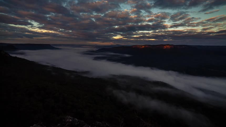 Timelapse of clouds floating over a foggy landscape