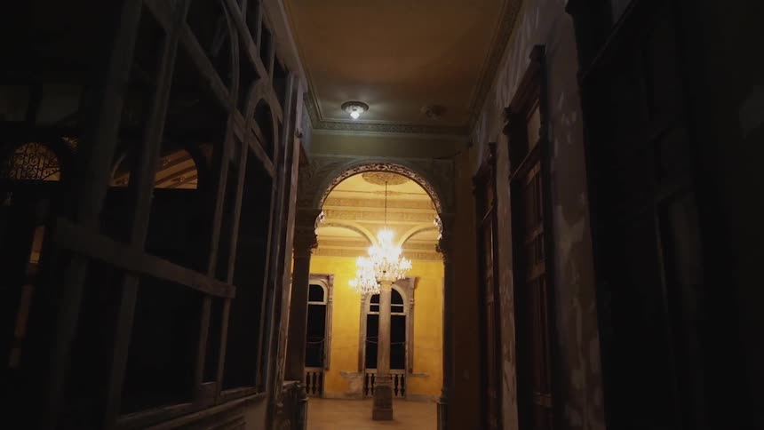 Dimly lit hallway going into a dining room with a chandelier