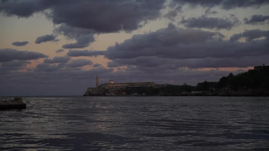 The sun is setting over the rough waters