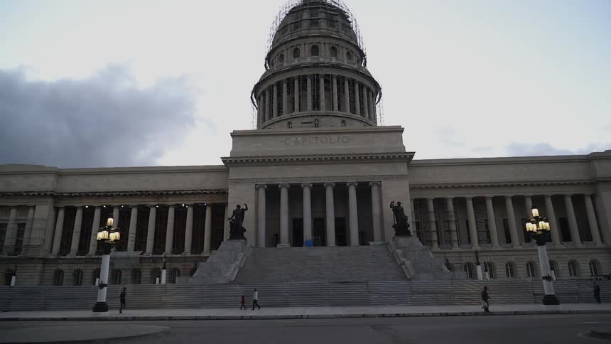 People walk in front of a large domed building
