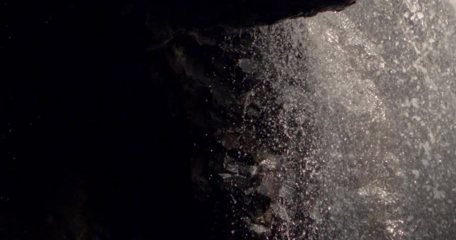 Water cascades over the opening of a cave