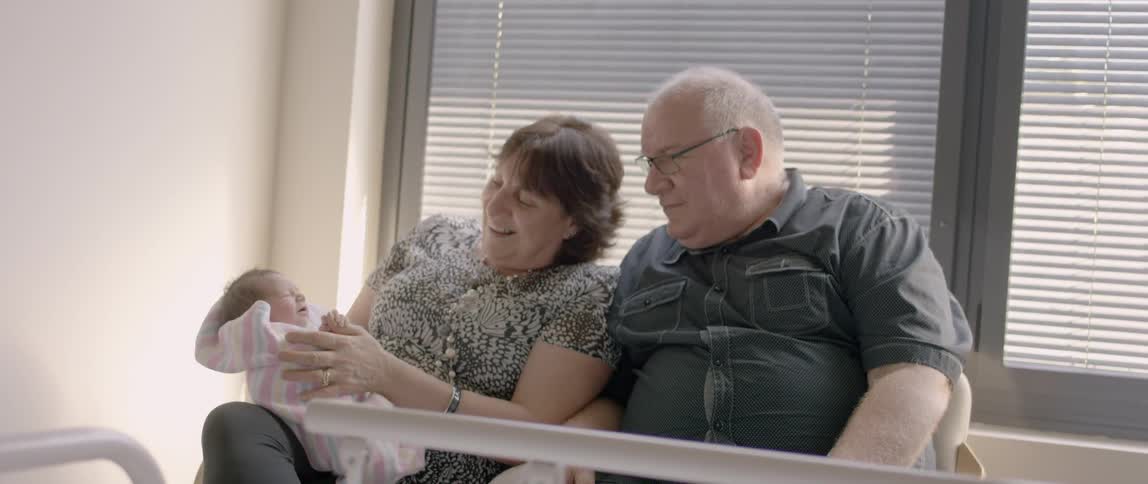 Elderly man and woman hold a crying infant