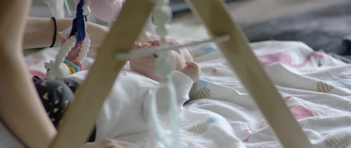 A baby cries while laying on the floor with baby toys