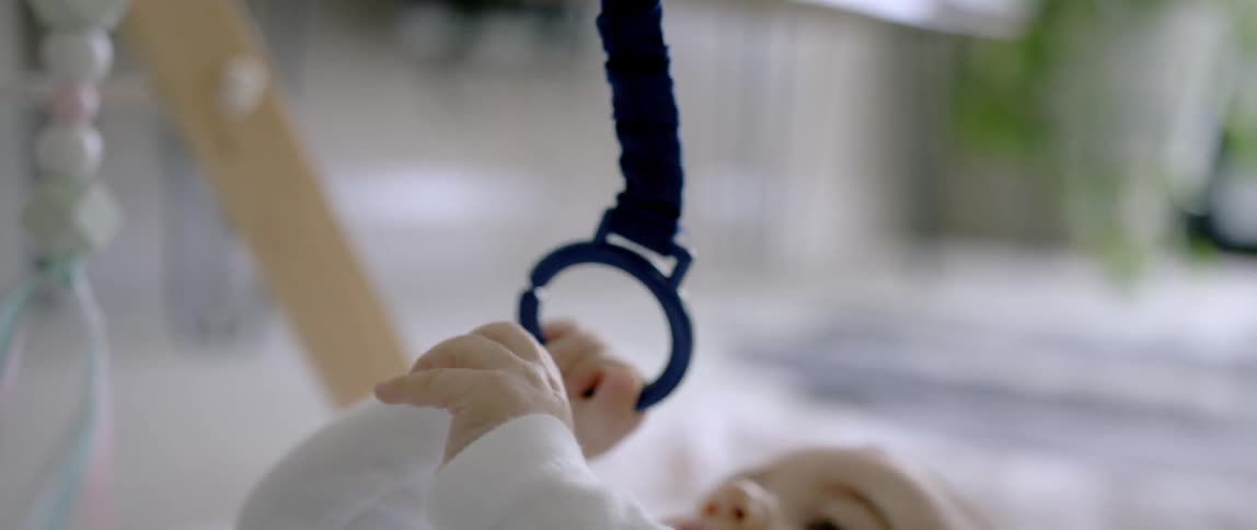 A baby lays on the floor and plays with a baby toy