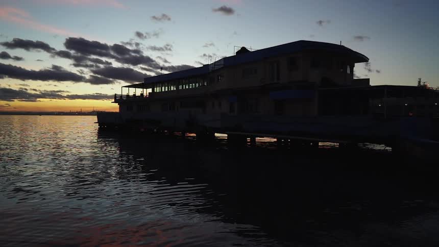 The sea flows around a building on a pier at sunset