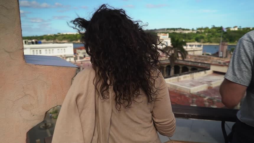 A woman walks over to the balcony on a cloudy day