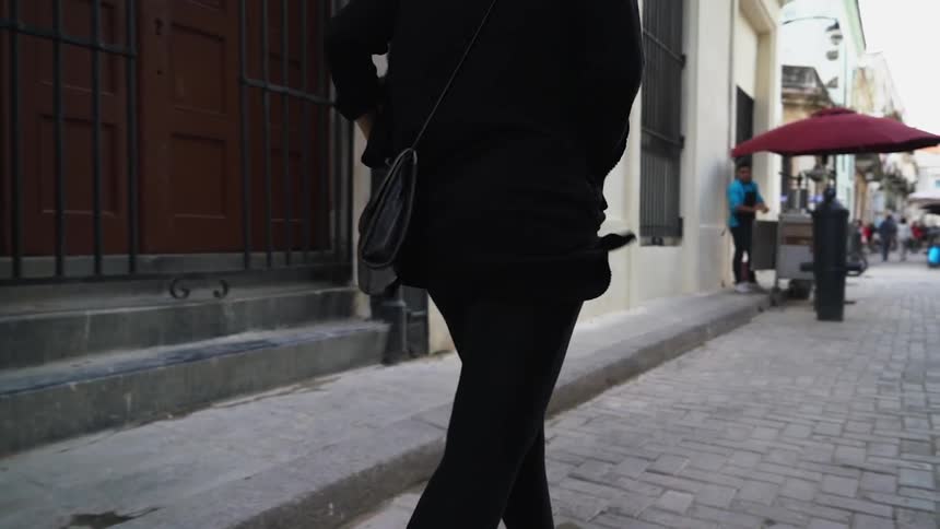 A woman walks down a stone sidewalk