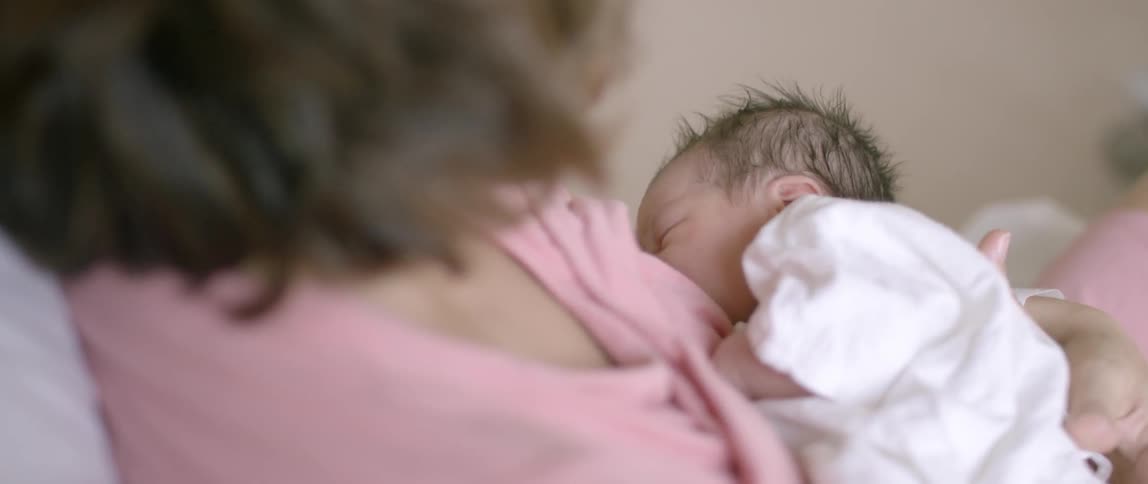 A mother holds and breast feeds her baby