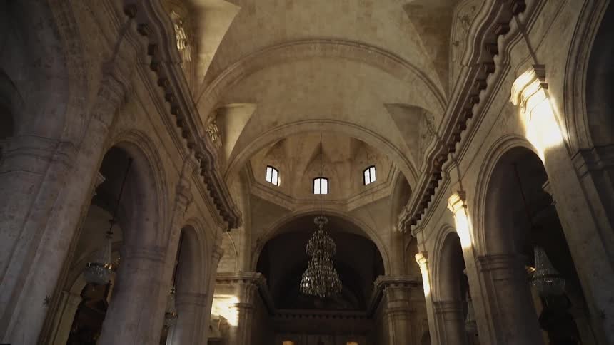 People worship and stand about in an old cathedral during the day