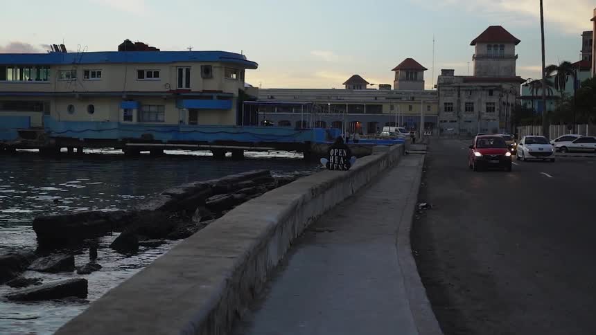 A person is sitting on a boardwalk wall near a road