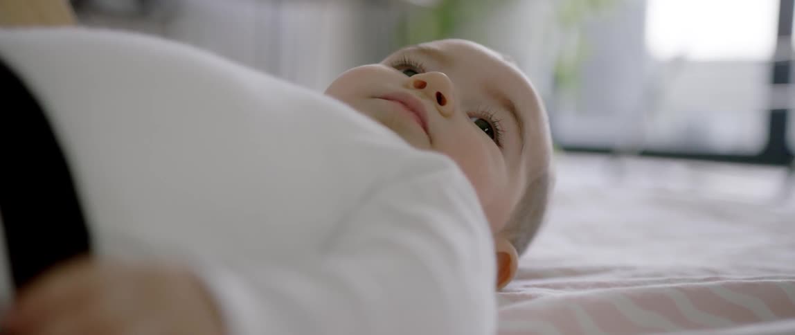 A baby lays on its back on a blanket
