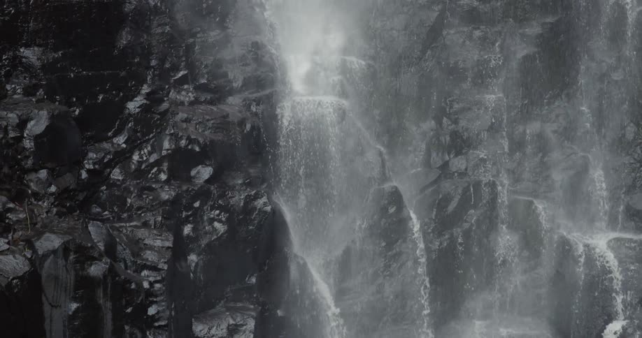 The side of the cliff has water falling down it