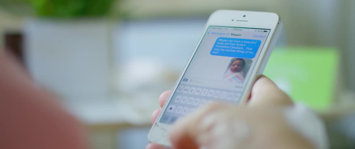 A picture of a newborn is shown with text messages on a phone