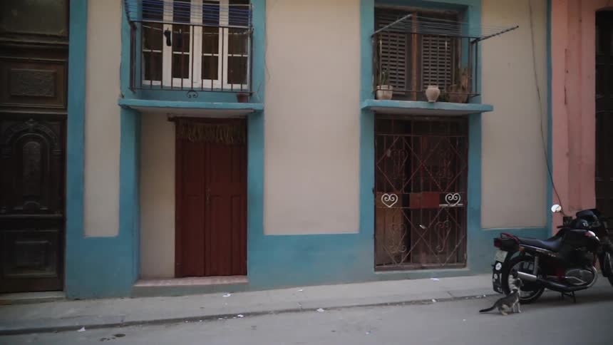 A motorcycle is parked next to a pink and blue building