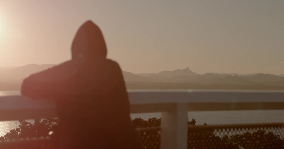 A person is looking at a view at sunset