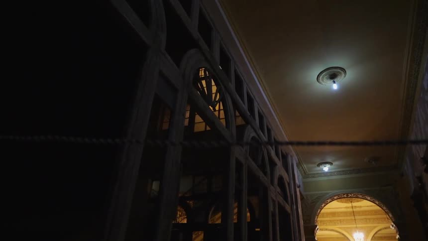 Lights shine on the ceiling of a dark building
