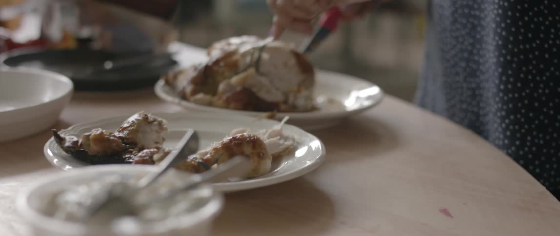 A woman carves meat off of a turkey