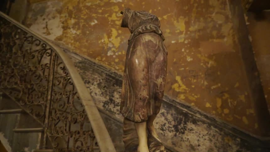 A statue sits on the balustrade at the bottom of some stairs