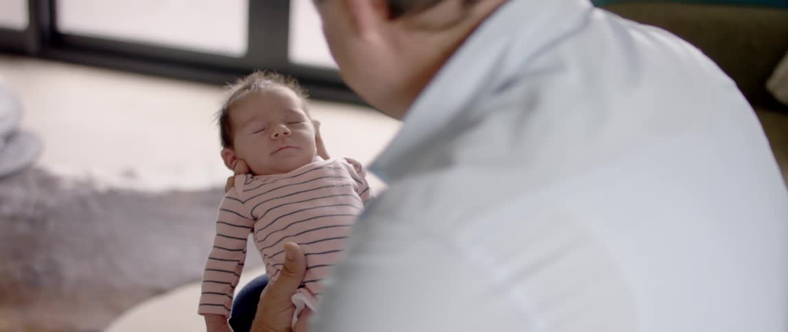 A man holds a small baby who is falling asleep