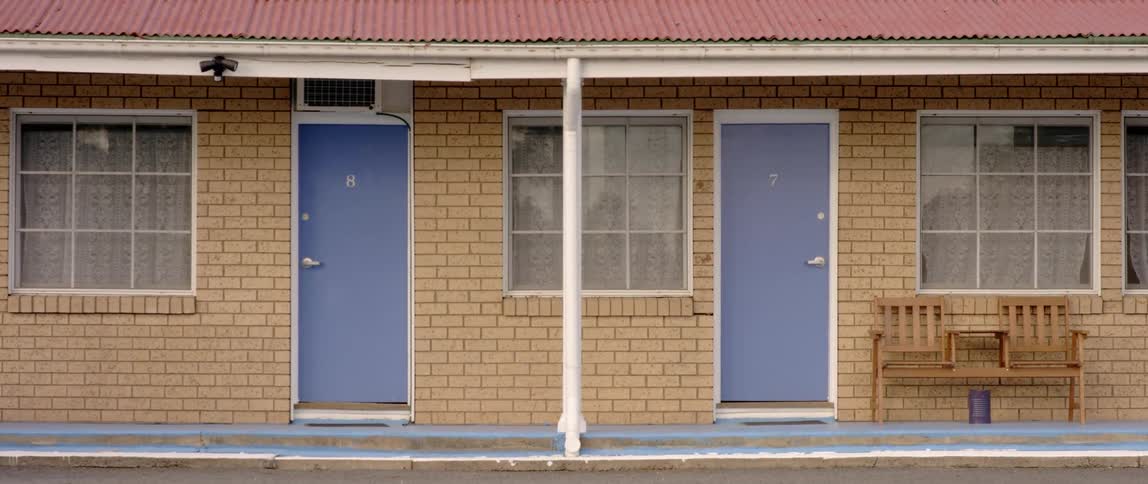 Close up of a yellow brick motel with blue doors