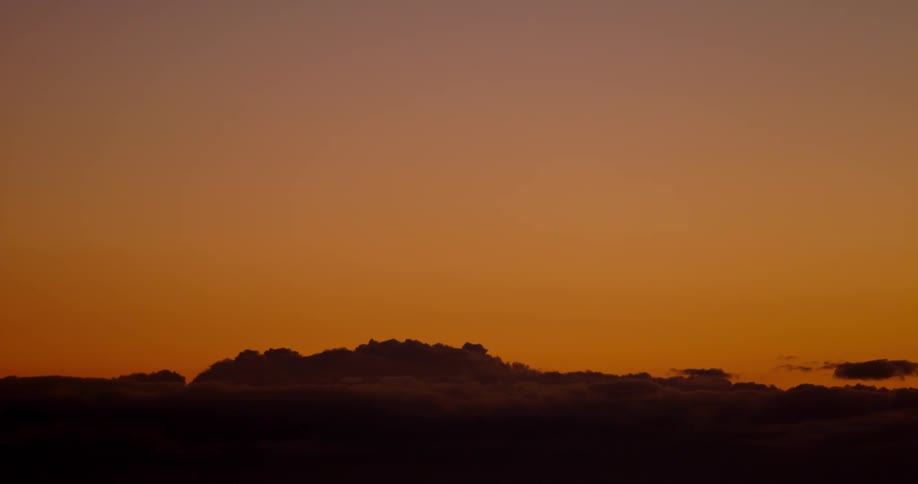 The setting sun lights the sky above the clouds